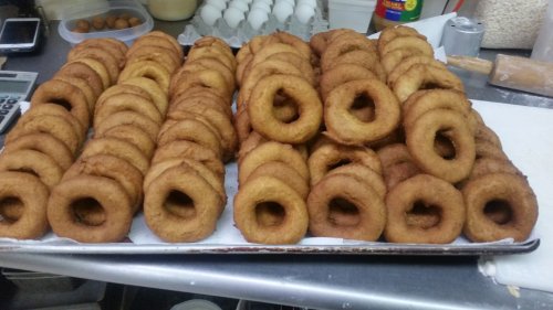 A tray of freshly fried donuts arranged in neat rows, showcasing their golden-brown color and circular shape.