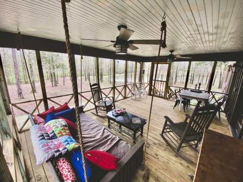 Cozy screened porch with rocking chairs, a swing, and a wooden table, surrounded by trees and natural light.