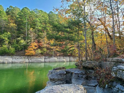A serene lake surrounded by colorful autumn trees and rocky shores under a clear blue sky.