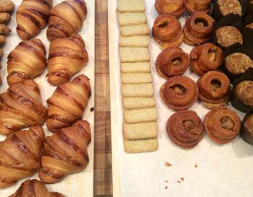 A variety of baked goods including croissants, cookies, and pastries arranged on a wooden surface.