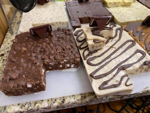 Two types of fudge on a marble surface: one chocolate with nuts, the other white with chocolate drizzle.