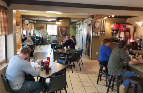 A cozy diner with patrons seated at tables and a counter, enjoying meals in a warm, inviting atmosphere.