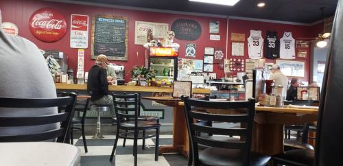 A cozy diner interior with red walls, a counter, and vintage decor, featuring customers seated at tables.