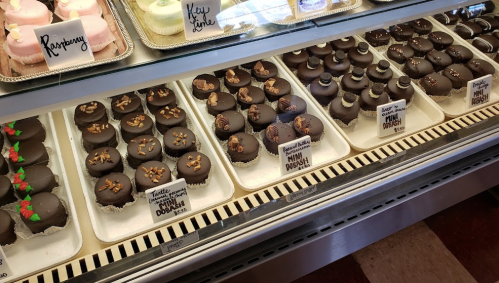 A display case filled with various chocolate-covered cupcakes, some decorated with nuts and festive designs.
