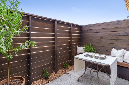 A cozy outdoor space with a wooden fence, a small table, and potted plants, creating a serene atmosphere.
