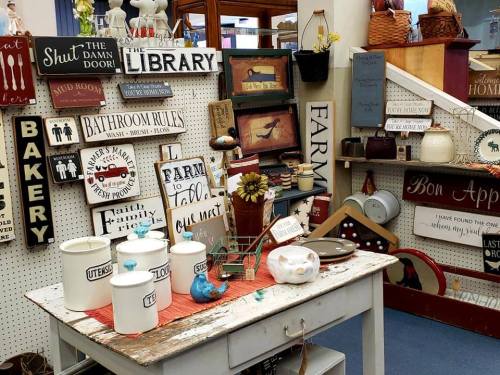 A cozy display of vintage signs and kitchenware on a rustic table in a charming shop.
