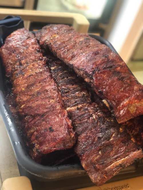 A tray of perfectly cooked, smoky barbecue ribs with a rich, caramelized glaze.