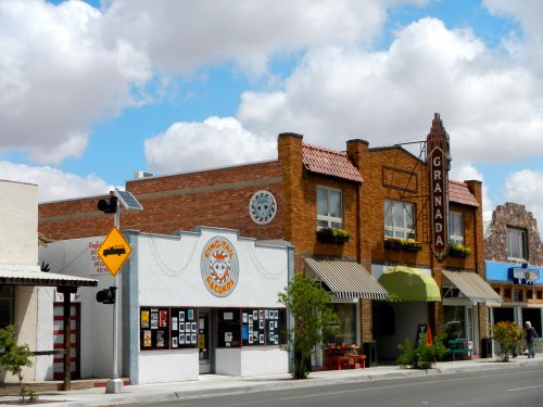 A street view of a small town featuring shops, including a record store and a building with a "Granada" sign.