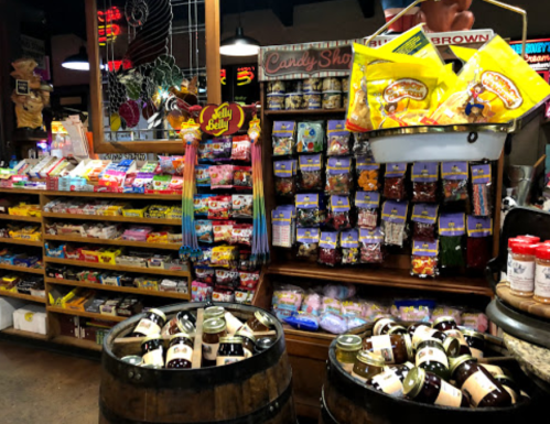 A colorful candy shop display with shelves of sweets, jars, and barrels filled with treats.