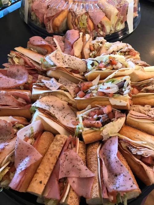 A large platter of assorted sandwiches with various meats, vegetables, and seasonings, arranged neatly.
