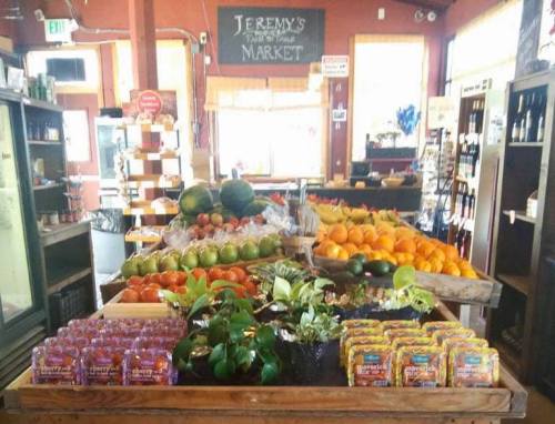 A vibrant market display featuring fresh fruits, vegetables, and packaged goods in a rustic setting.