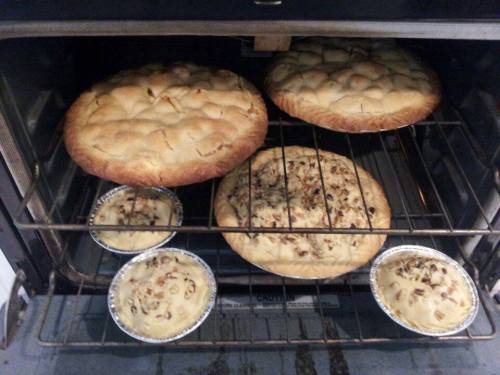 Two large baked goods and two smaller pies are cooling in an oven.