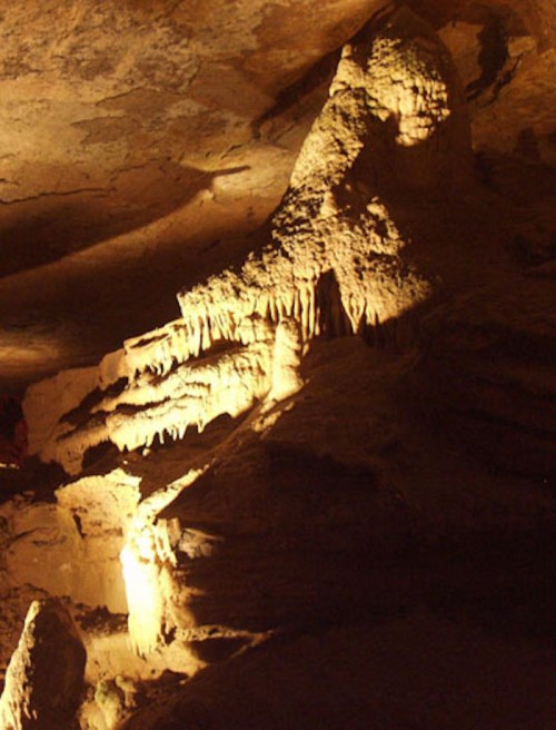 A dimly lit cave interior featuring unique rock formations and shadows creating an intriguing atmosphere.