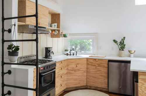 Modern kitchen with wooden cabinets, stainless steel appliances, and a bright window, featuring a cozy, minimalist design.