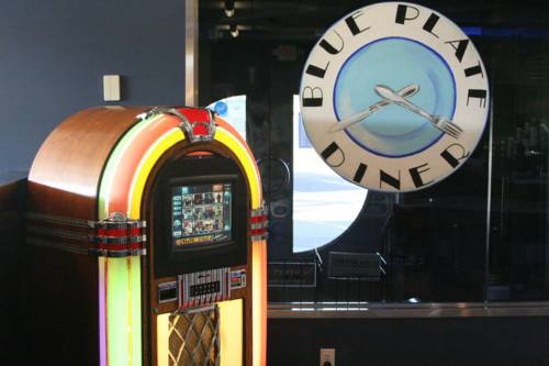 A colorful jukebox next to a sign for the Blue Plate Diner, featuring a fork and knife design.