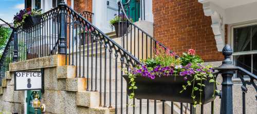 A staircase with decorative iron railings and flower boxes, leading to an office entrance.