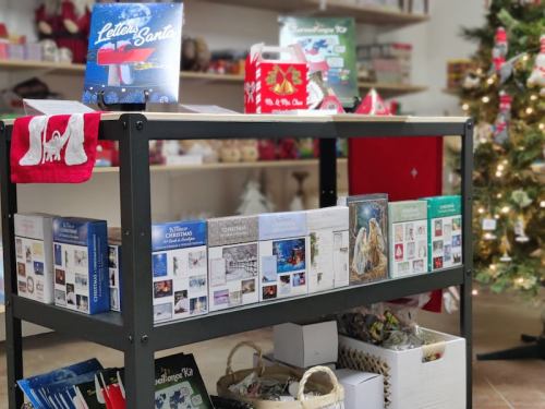 A display shelf with holiday decorations, including Christmas cards and a "Letters to Santa" book, beside a decorated tree.