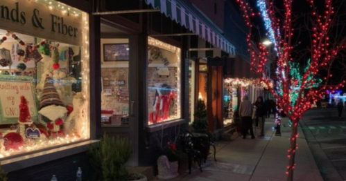 A festive street scene with shops decorated in colorful holiday lights and a tree adorned with bright lights.