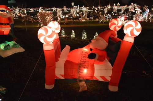 A festive scene with inflatable Santa on a candy cane bed, surrounded by colorful holiday lights and decorations.