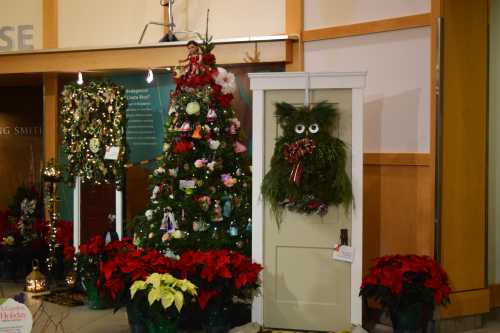 A festive display featuring a decorated Christmas tree, a whimsical wreath on a door, and poinsettias.