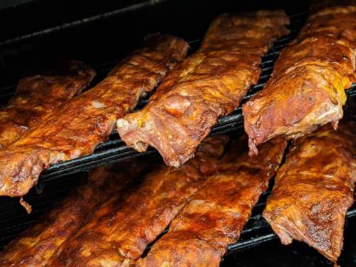 Close-up of grilled ribs on a rack, showcasing a smoky, caramelized exterior.
