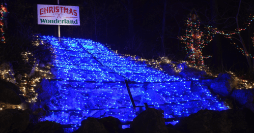 A pathway illuminated with blue lights, leading to a sign that reads "Christmas Wonderland" in a festive setting.