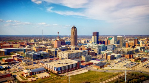 Aerial view of a city skyline featuring tall buildings, blue skies, and scattered clouds.