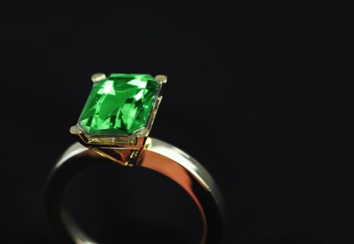 A close-up of an elegant ring featuring a large emerald-cut green gemstone set in a gold and silver band.