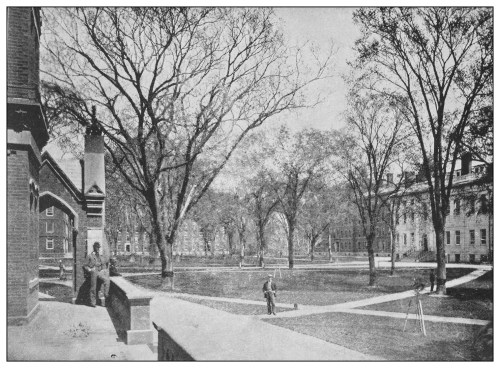Historic black-and-white photo of a college campus with bare trees, a grassy area, and students walking.