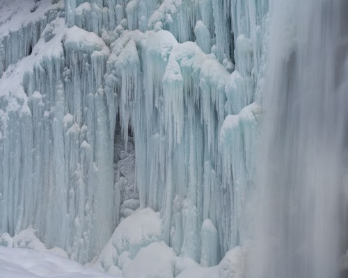 Icicles and frozen formations cascade down a rocky surface, creating a stunning icy landscape.