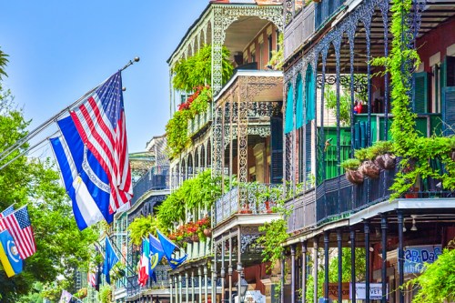 Colorful balconies adorned with greenery and flags in a vibrant street scene, showcasing historic architecture.
