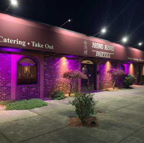 Exterior of Hong Kong Buffet at night, featuring purple lighting and signage for catering and takeout services.