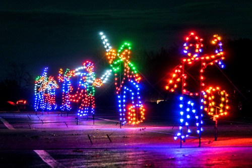 Colorful illuminated figures in festive attire playing instruments, set against a dark evening sky.