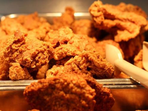 A close-up of crispy, golden-brown fried chicken pieces in a serving tray.