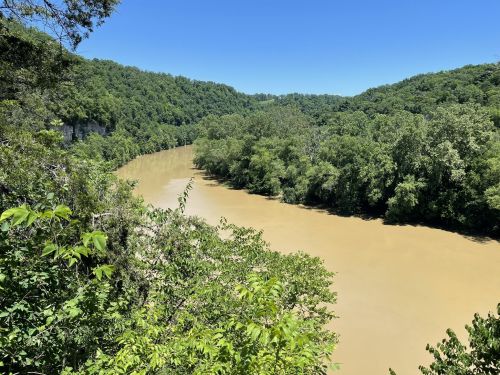 A winding river flows through lush green hills under a clear blue sky.