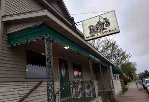Exterior of a restaurant with a green awning and a sign that reads "Rita's Dining & Cocktails." Overcast sky.