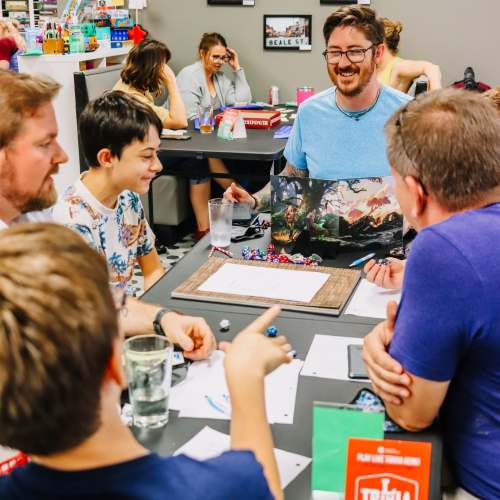 A group of friends gathers around a table, playing a tabletop game with dice and character sheets. Laughter fills the air.