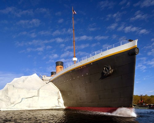 A large ship, resembling the Titanic, approaches a massive iceberg under a blue sky with scattered clouds.