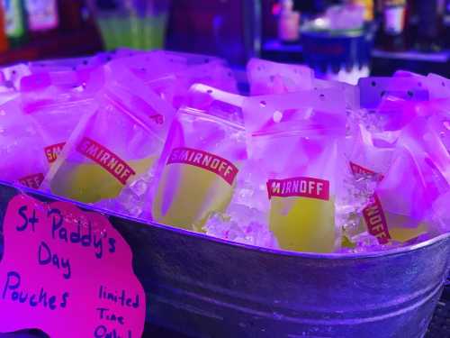 A metal tub filled with ice and Smirnoff drink pouches, with a sign for St. Paddy's Day limited-time offer.