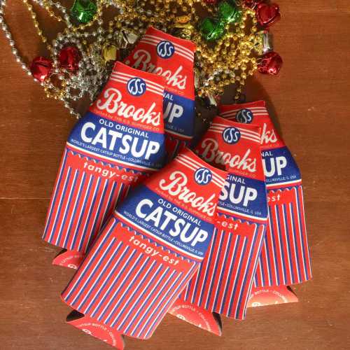 A collection of vintage-style ketchup bottle cutouts in red and white, arranged on a wooden surface with festive decorations.