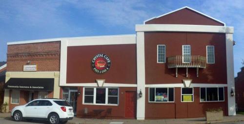 Exterior view of a two-story building with a red facade, featuring a balcony and a sign for "Crystal Cafe."