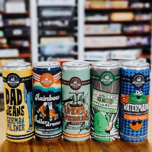 Five colorful beer cans lined up on a wooden table, featuring unique designs and names like "Dad Jeans" and "Watermelon Wut."