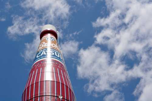 A large, iconic ketchup bottle-shaped structure against a blue sky with clouds.