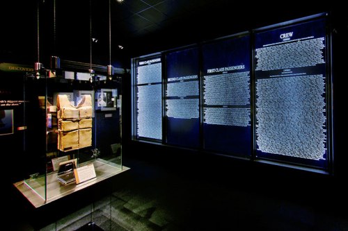 Exhibit featuring a life vest and panels listing passengers and crew in a dimly lit museum setting.