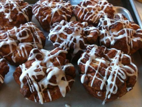 Freshly baked cinnamon rolls drizzled with white icing, arranged on a baking tray.