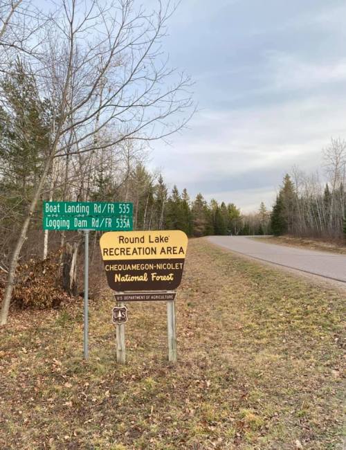 Sign for Round Lake Recreation Area, Chequamegon-Nicolet National Forest, near a road with directional signs.
