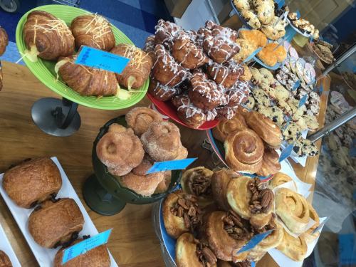 A display of assorted pastries, including croissants, muffins, and cinnamon rolls, on colorful plates.