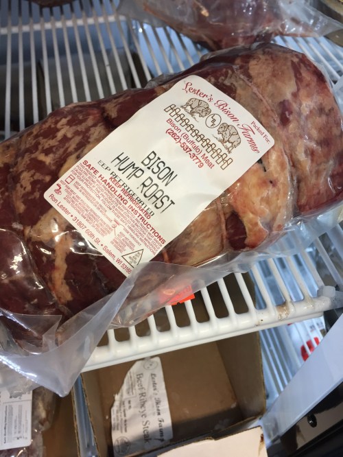 A packaged bison hump roast on a shelf, labeled with product details and cooking instructions.
