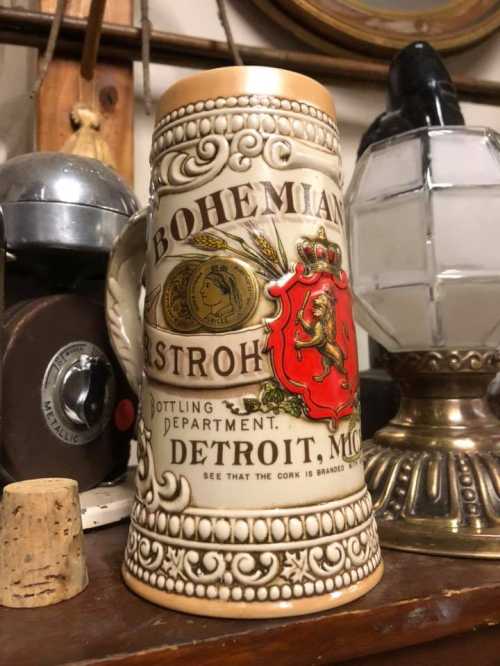 A decorative beer stein featuring "Bohemian Astroh" and a lion emblem, with vintage decor in the background.