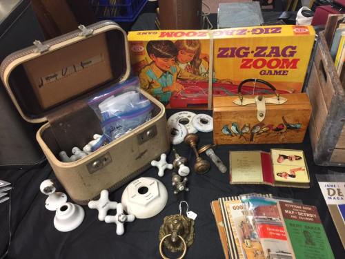 A collection of vintage items including a game box, a wooden bird-themed box, and various old tools and books.